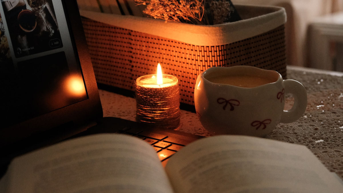 Cup of coffee by candlelight next to an open book