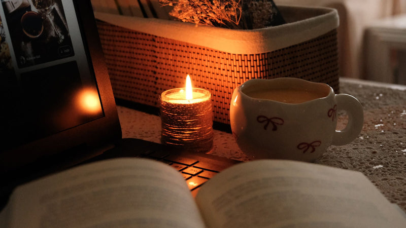 Cup of coffee by candlelight next to an open book
