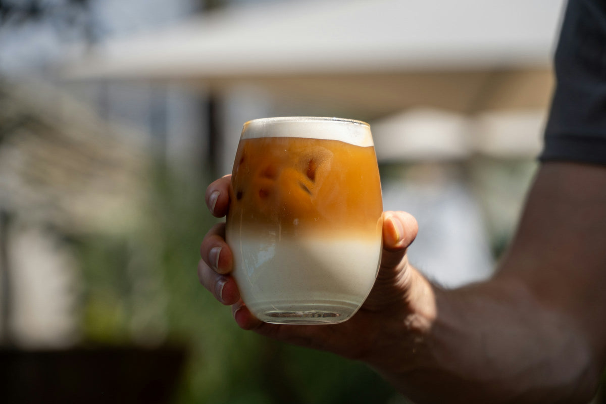 Hand holding a layered iced coffee with milk